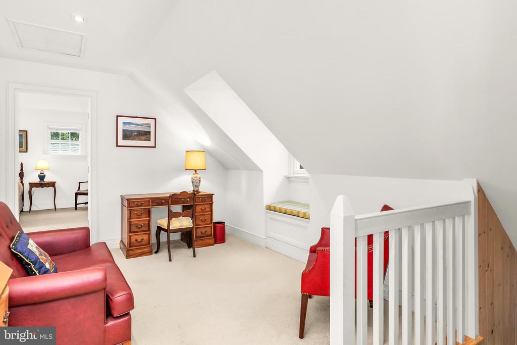 Upstairs sitting room with red leather seating, a wooden desk, and a sloped ceiling.