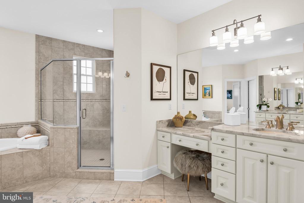 Bathroom with a glass shower, tiled soaking tub, and long white vanity.