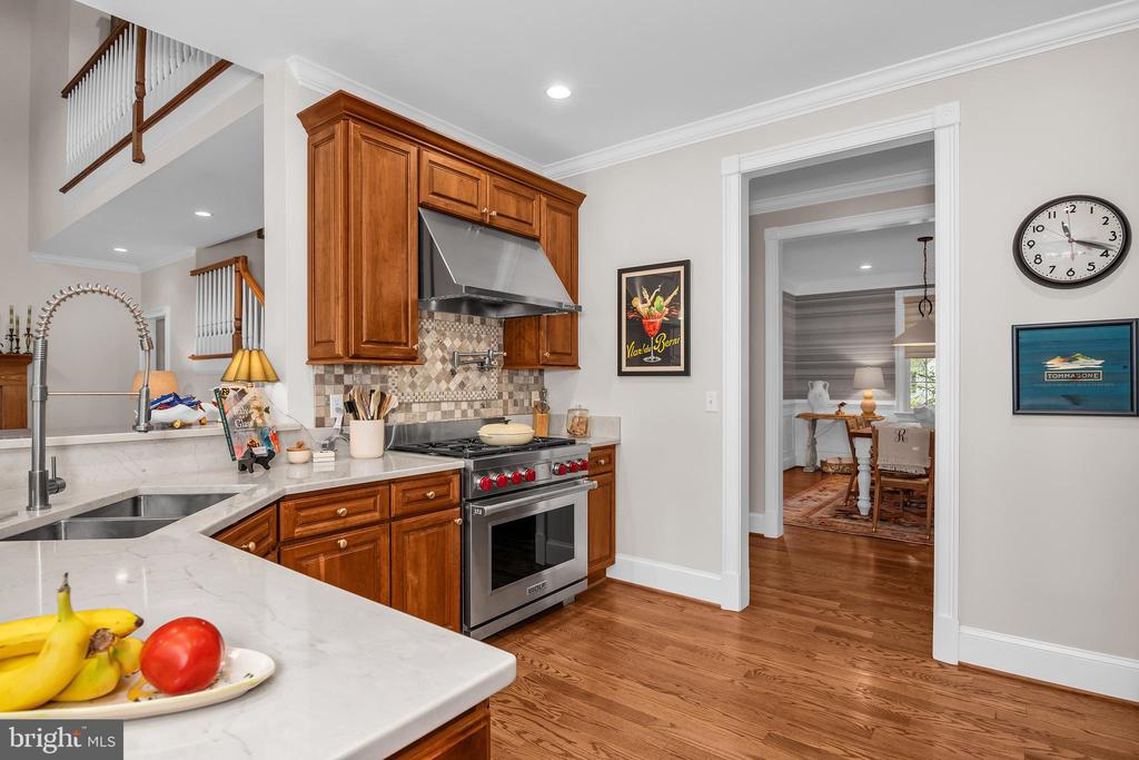Kitchen with wood cabinetry, white counters, stainless steel range, and a doorway to the dining area.