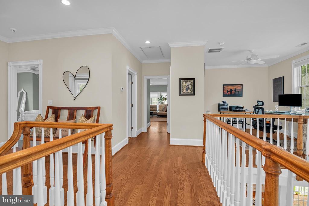 Upstairs landing with hardwood floors, wood handrails, white balusters, and a small office area.