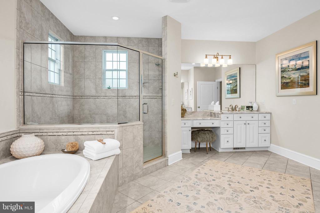 Bathroom with a glass-enclosed tiled shower, soaking tub, and white double vanity.