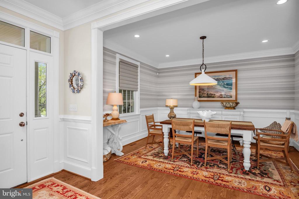 Dining room with striped wallpaper, a wooden table, and a patterned rug.