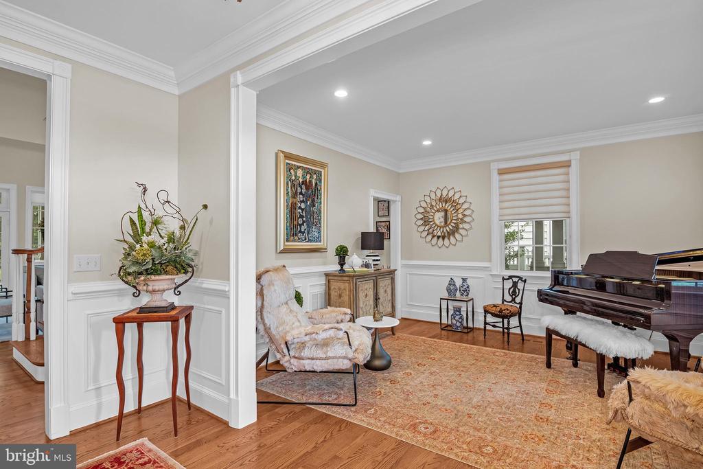 Living room with a grand piano, patterned rug, and white wainscoting.