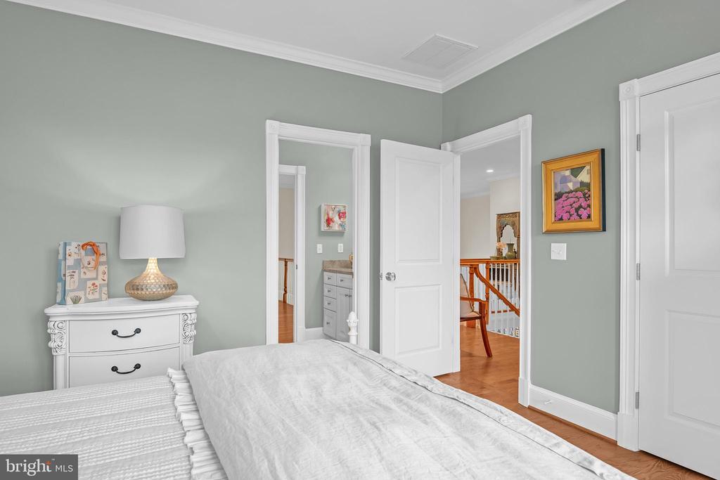 Bedroom with sage-green walls, white bedding, and open doorways to adjoining rooms.