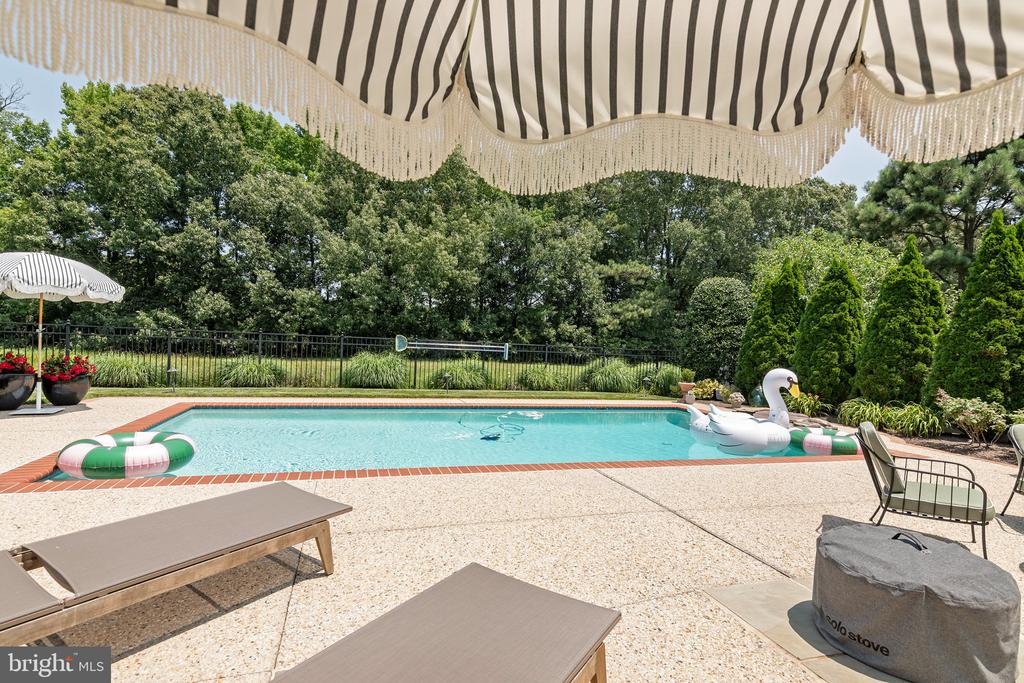 Backyard swimming pool with striped umbrellas, lounge chairs, and colorful floats.