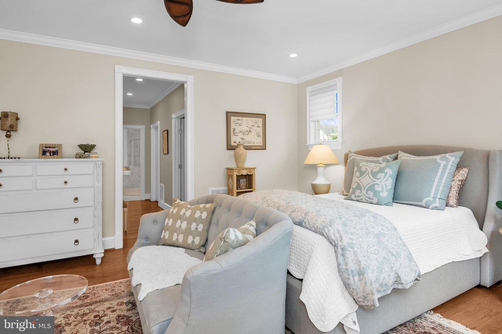 Bedroom with pale blue bedding, an upholstered chair, and a white dresser.