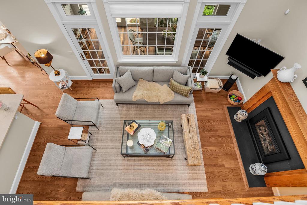 Overhead living room with gray seating, hardwood floors, tall windows, and a fireplace.