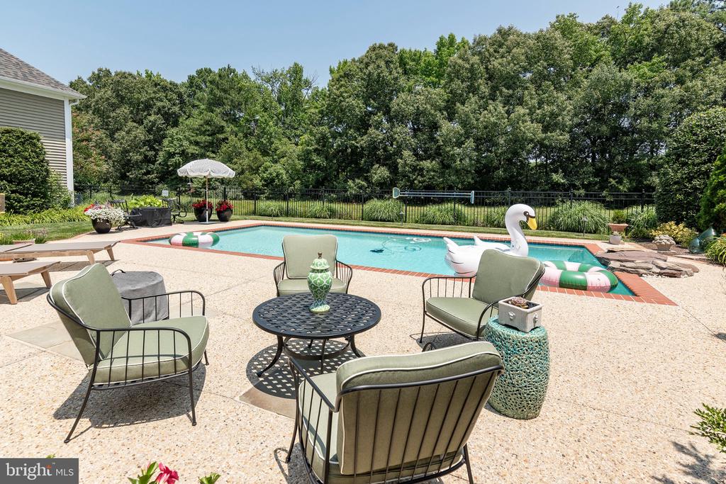 Outdoor pool with a swan float and lounge seating on a sunny patio.