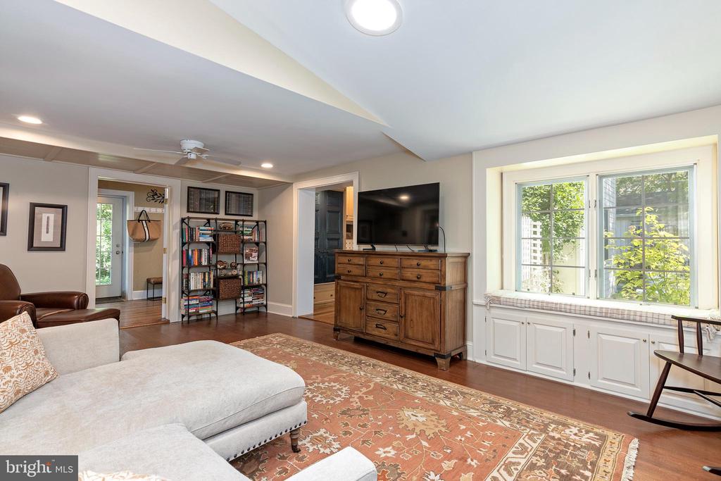 Furnished living room with a light sectional sofa, patterned rug, and wide window above built-in cabinets.