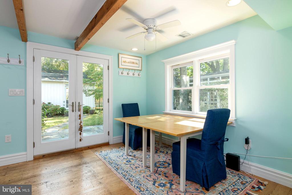 Dining area with aqua walls, exposed beams, and a wooden table beside French doors and windows.