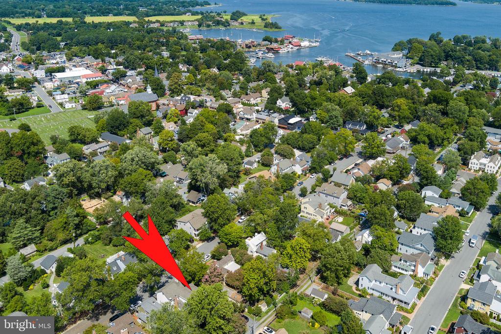 Aerial view of the property marked by a red arrow, with the waterfront and marina beyond.