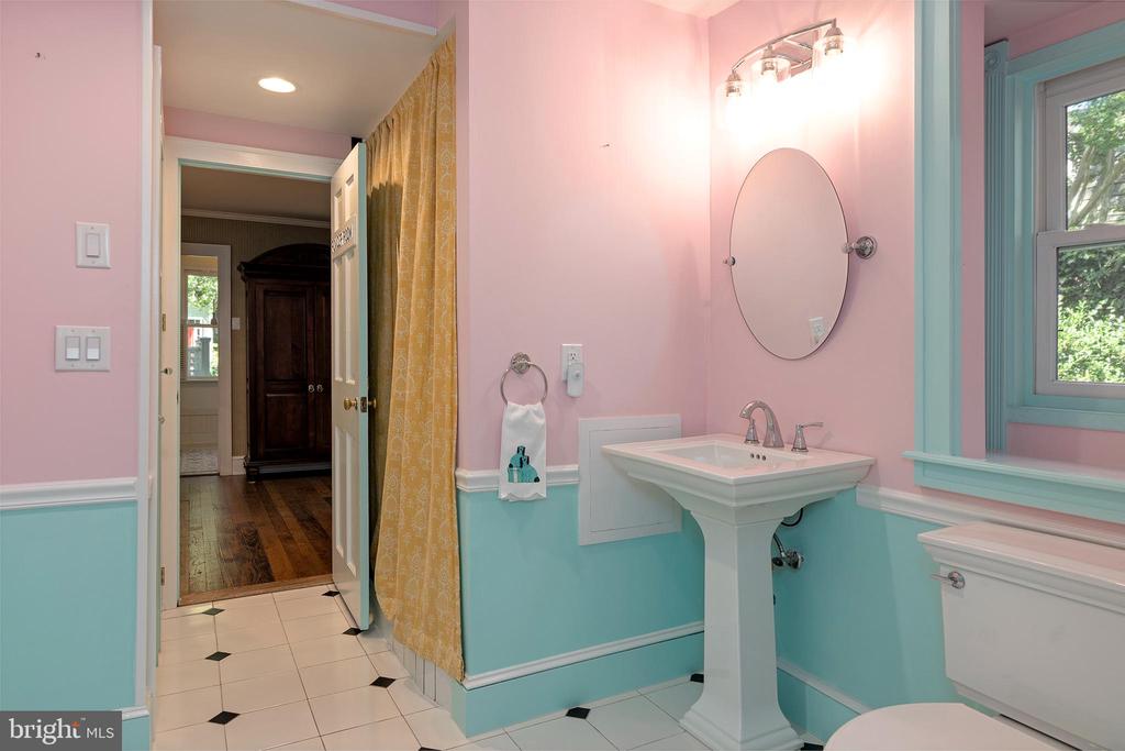Bathroom with a white pedestal sink, pink and turquoise walls, and black-accented tile floor.