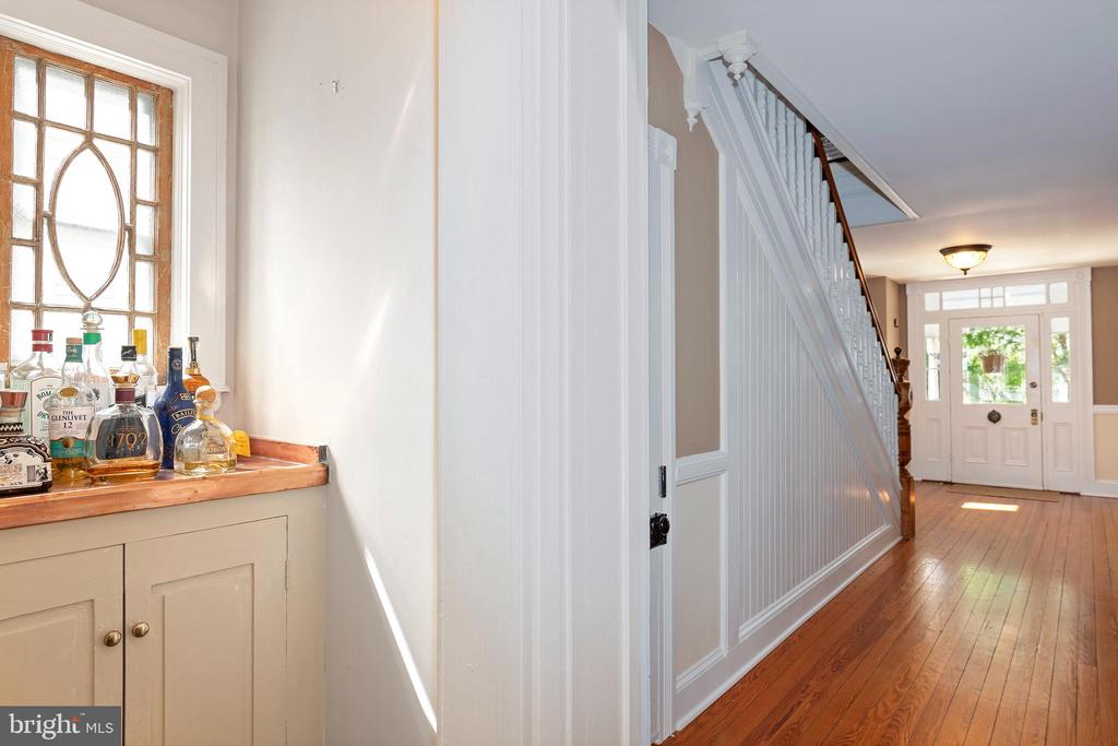 Entry hall with a white staircase, hardwood floors, and a built-in cabinet beneath a decorative window.