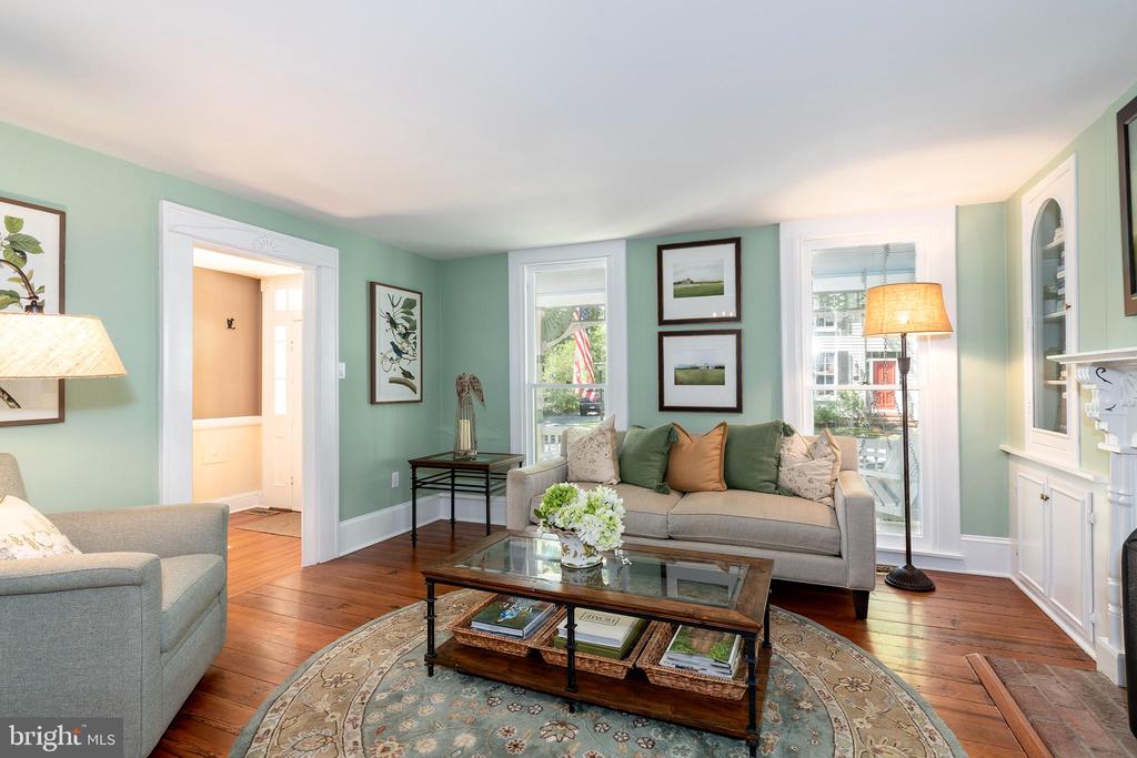 Living room with mint-green walls, a gray sofa, hardwood floors, and a glass coffee table.