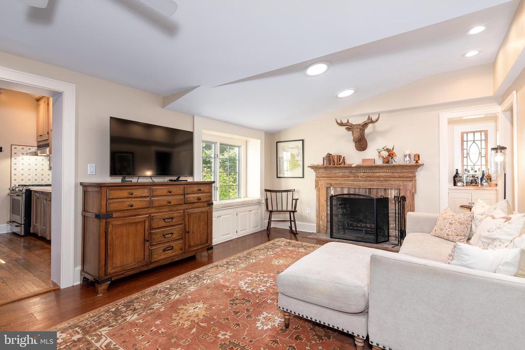 Living room with a carved wood fireplace, mounted television, pale sectional, and patterned rug.