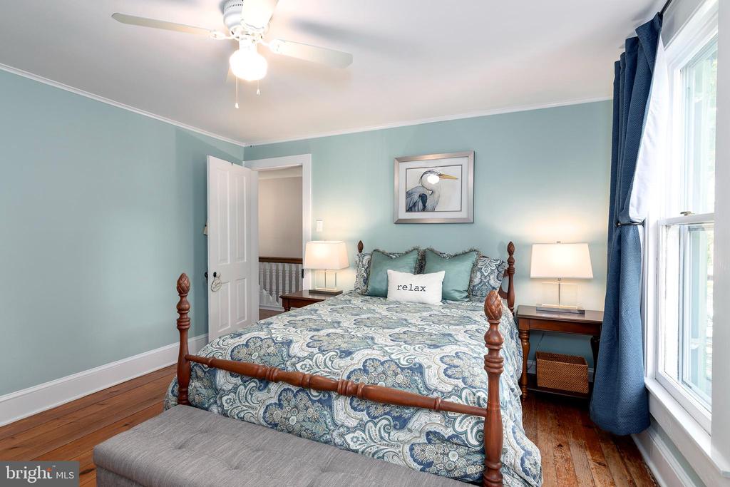 Bedroom with a wooden four-poster bed, patterned bedding, pale blue walls, and navy curtains.