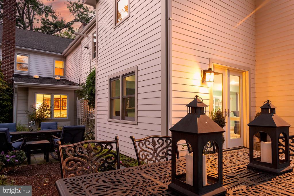 House courtyard patio with ornate metal dining table, lanterns, and warmly lit doors at dusk.