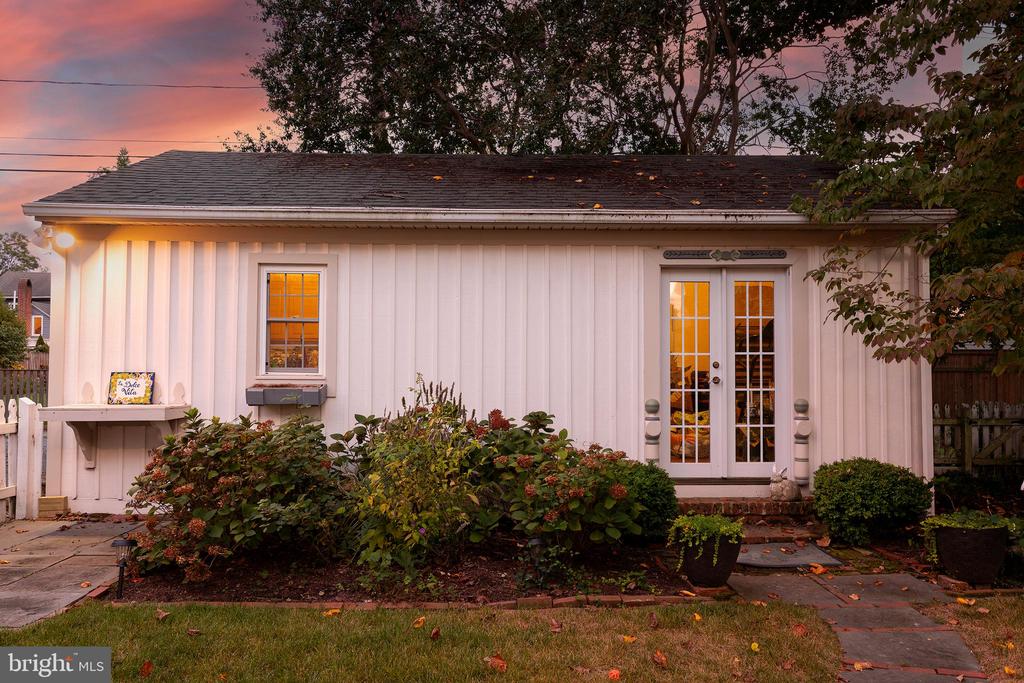 White-sided home exterior with French doors and autumn landscaping at dusk.