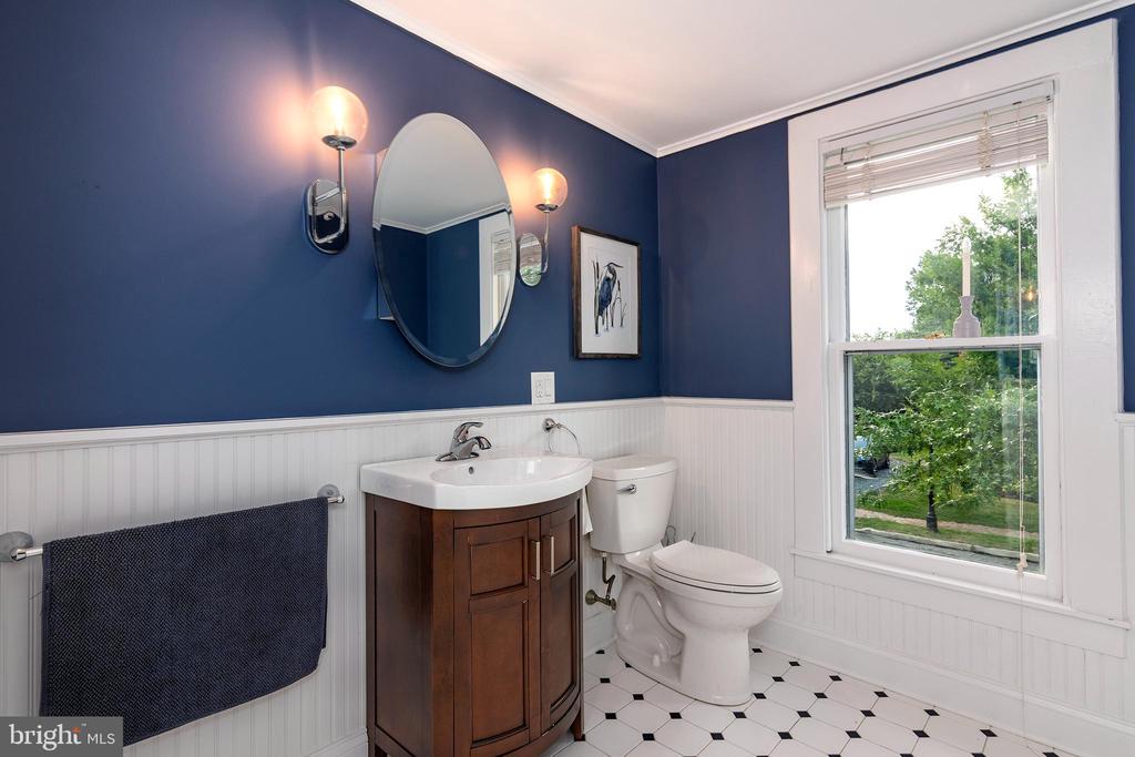 Bathroom with a dark wood vanity, navy walls, and a large window overlooking greenery.