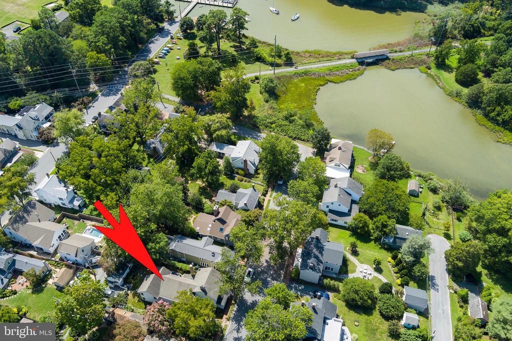 Aerial view of a house marked by a red arrow beside a pond.