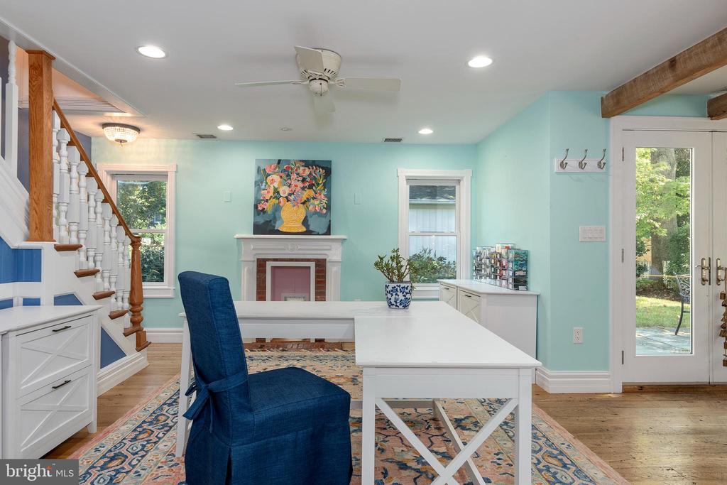 Dining area with turquoise walls, a white table, fireplace, and staircase beside glass garden doors.