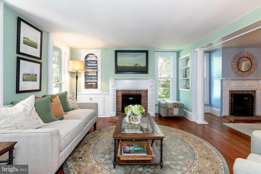 Living room with mint-green walls, two fireplaces, a gray sofa, and a glass coffee table.