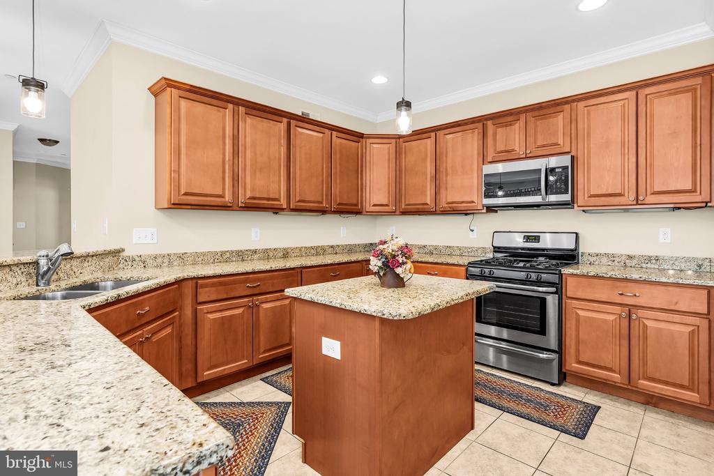 Kitchen with wood cabinets, granite counters, a central island, and stainless steel appliances.