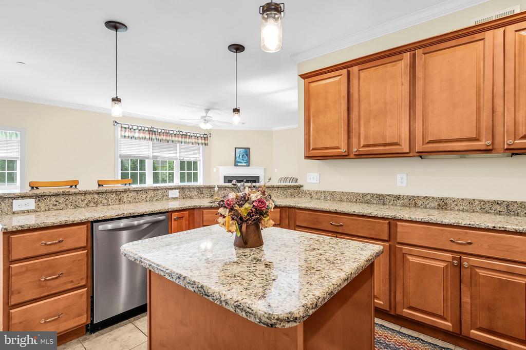 Kitchen with a granite island, warm wood cabinetry, and stainless-steel dishwasher.