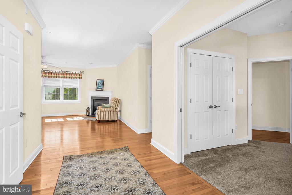 Living room with hardwood floors, a fireplace, and a striped armchair, viewed from the entryway.