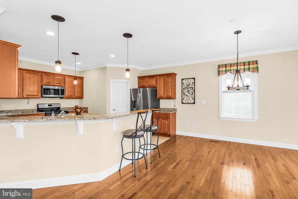 Kitchen with wood cabinets, granite breakfast bar, stainless steel appliances, and hardwood floors.