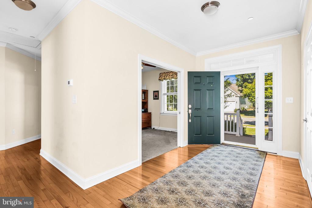 Front entry foyer with hardwood floors, patterned runner rug, and teal door with glass sidelights.