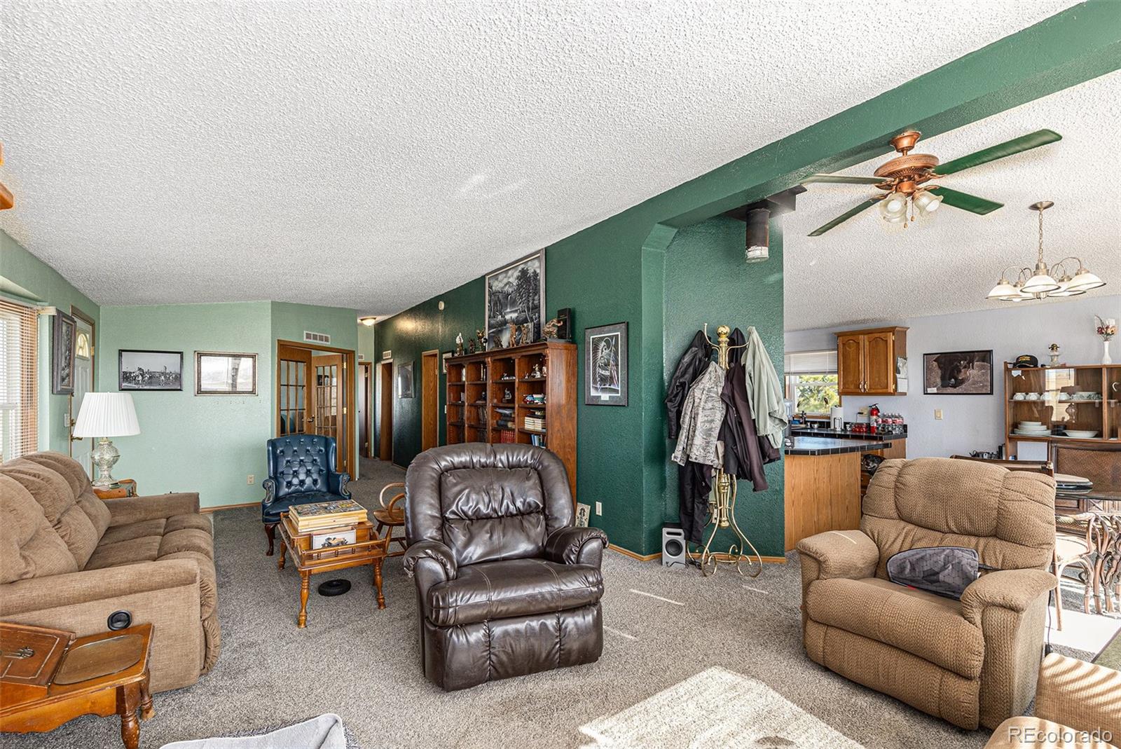 Living room with green walls, a ceiling fan, and several upholstered seating areas.