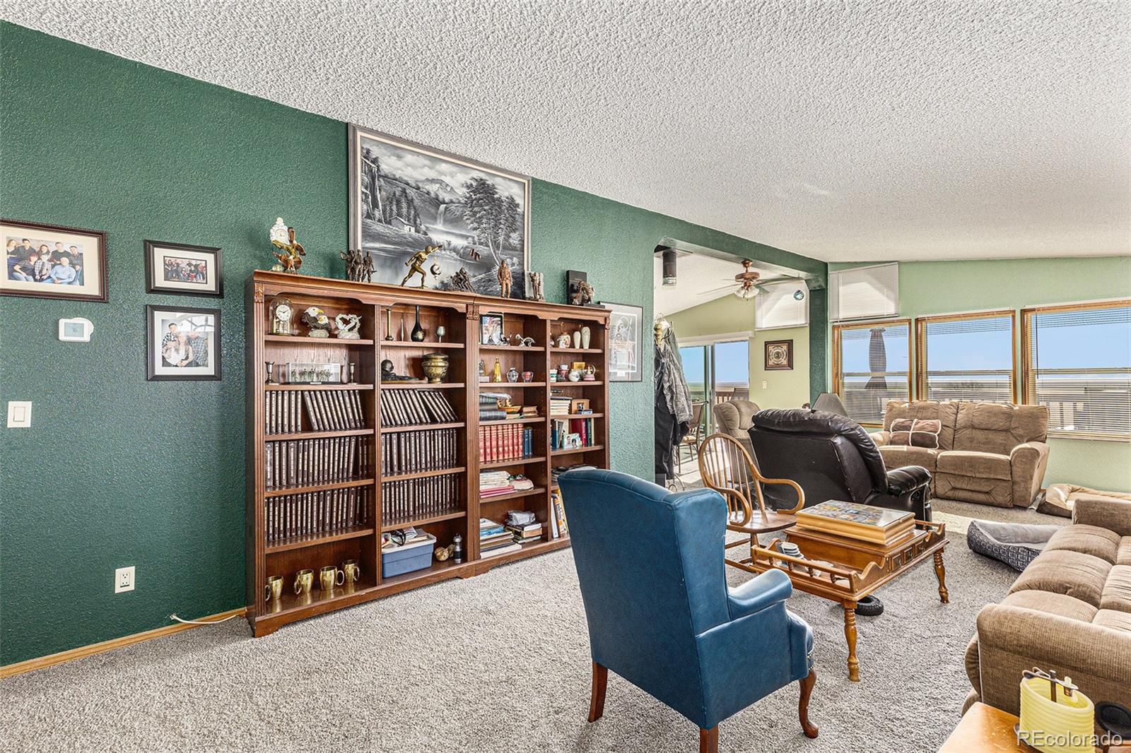Living room with a large wooden bookcase, green walls, and several seating areas.