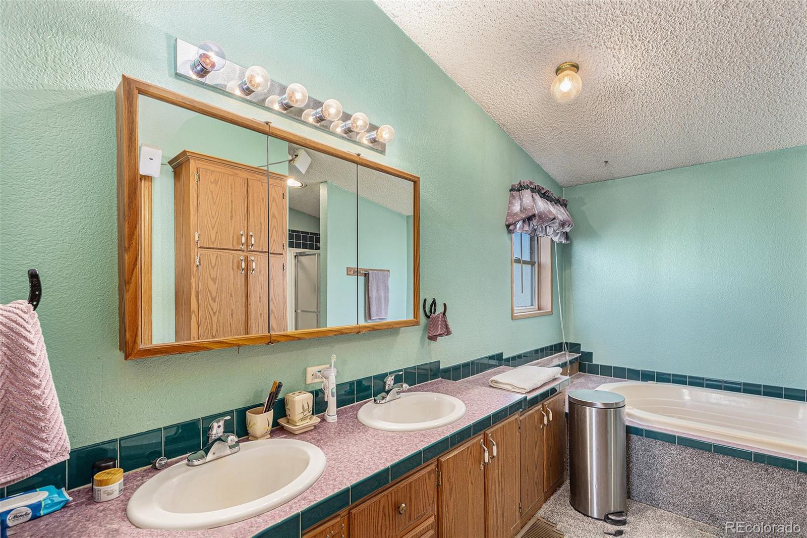 Bathroom with a double-sink vanity, wood cabinets, and a bathtub.