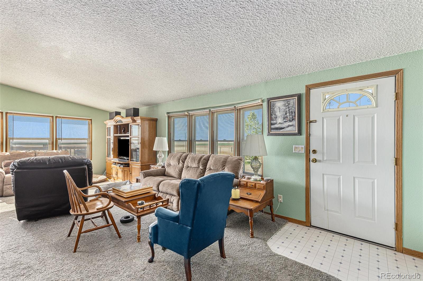 Living room with multiple seating areas and large windows overlooking open rural land.