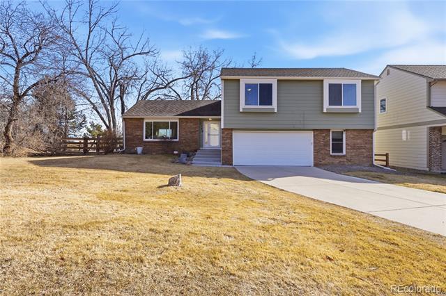 Two-story gray-and-brick house with a white garage and wide driveway beside a dry lawn.