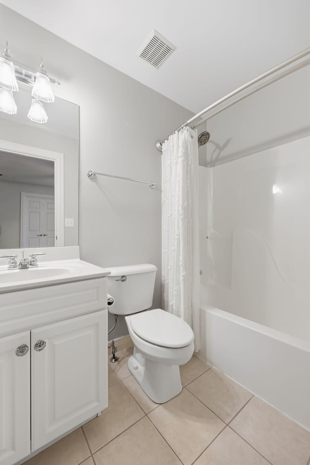 Bathroom with white vanity, toilet, and tub-shower behind a curtain.