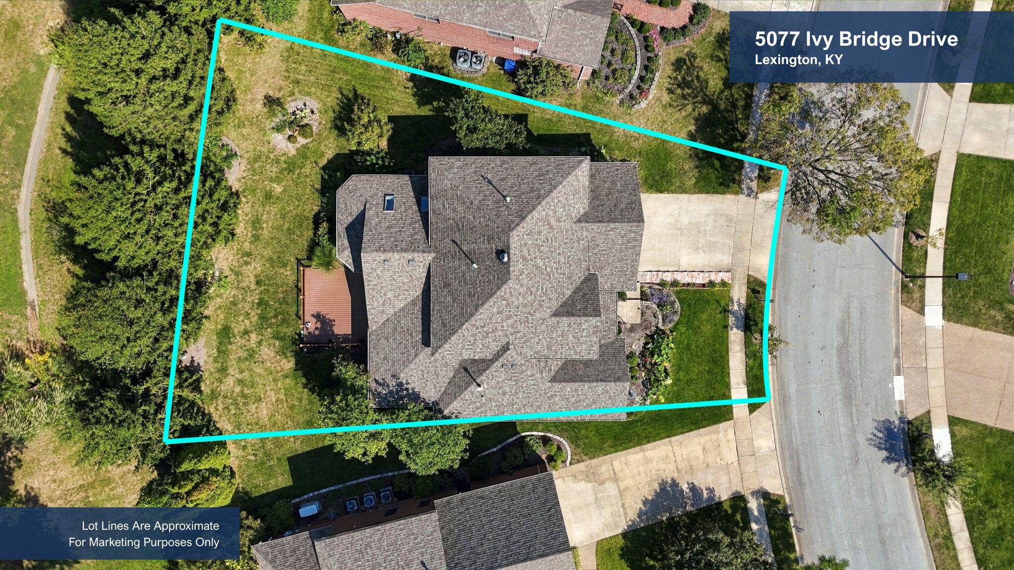 Aerial view of a home and yard outlined by approximate turquoise lot lines, with the driveway and surrounding trees visible.