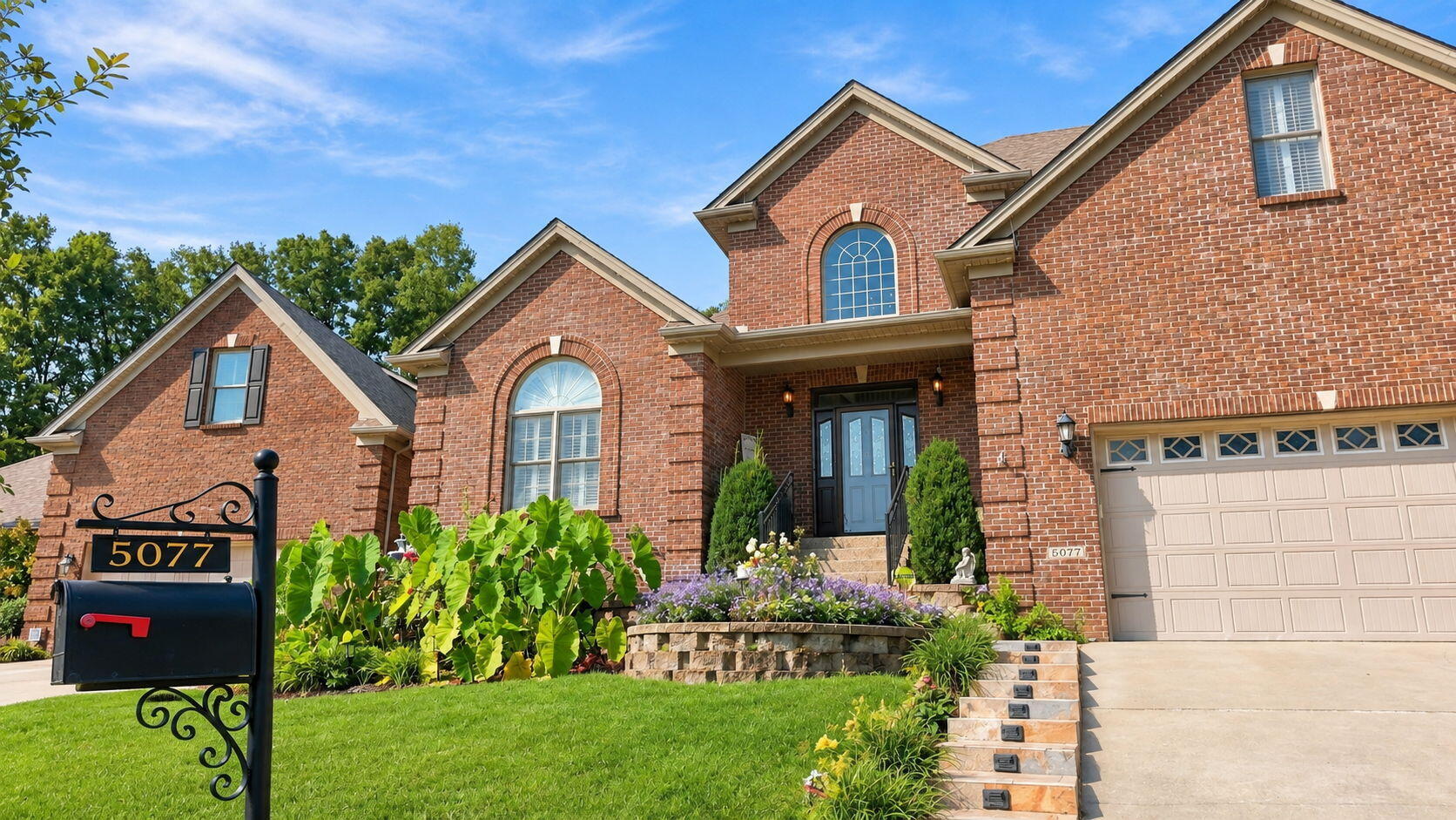 Two-story brick home with arched windows, landscaped garden, and attached double garage.