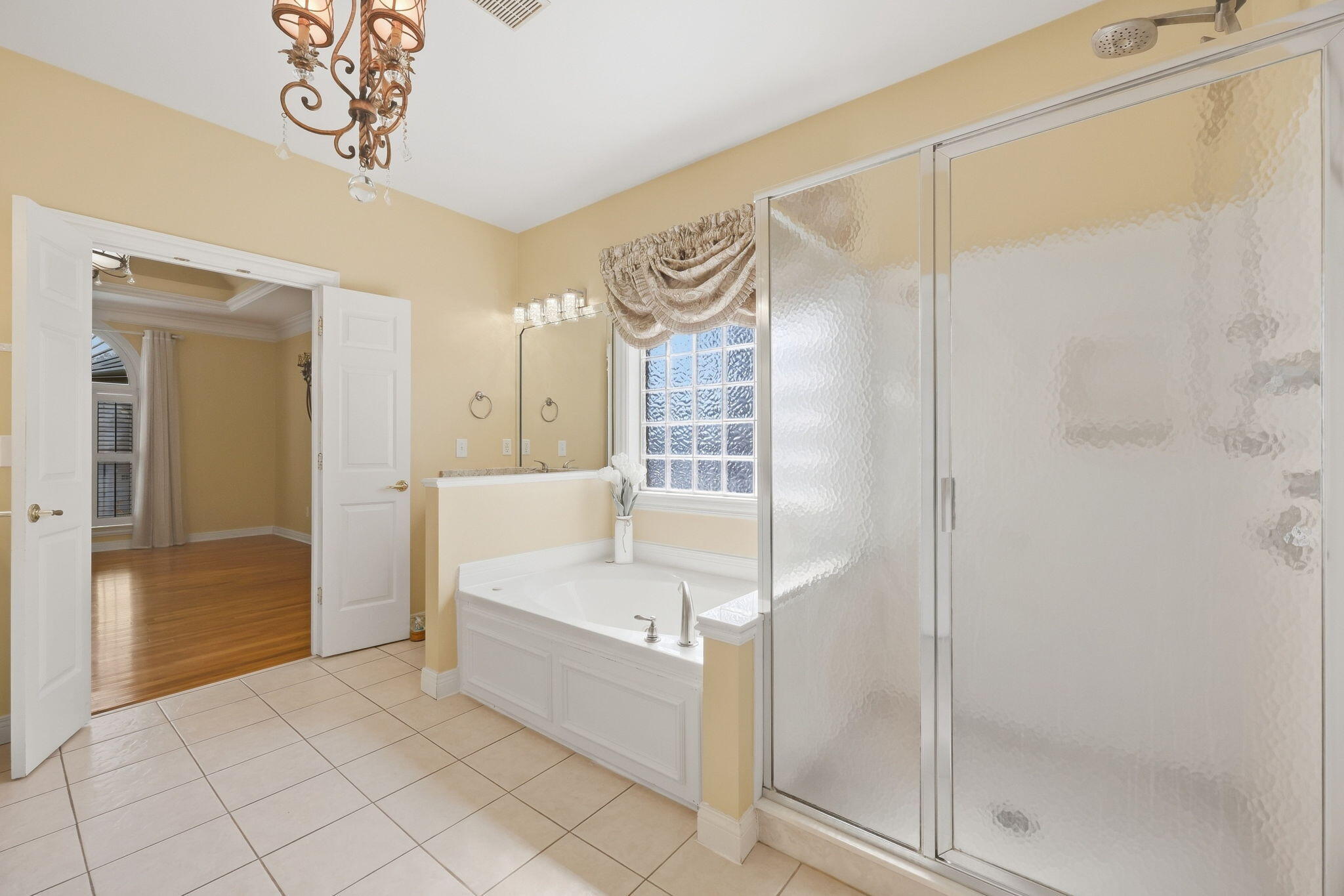 Bathroom with a soaking tub, glass-block window, and frosted-glass shower enclosure.