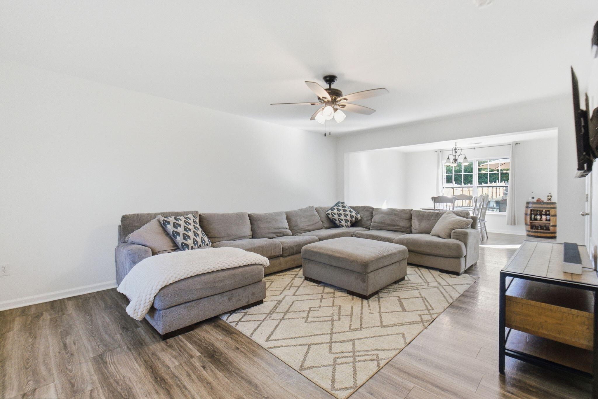 Living room with a gray sectional, geometric rug, and adjoining dining area.