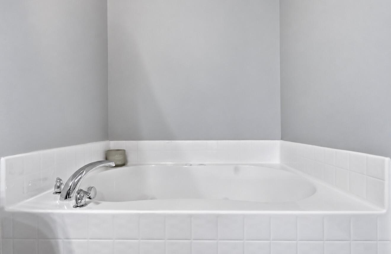 White built-in bathtub with chrome fixtures and tiled surround.