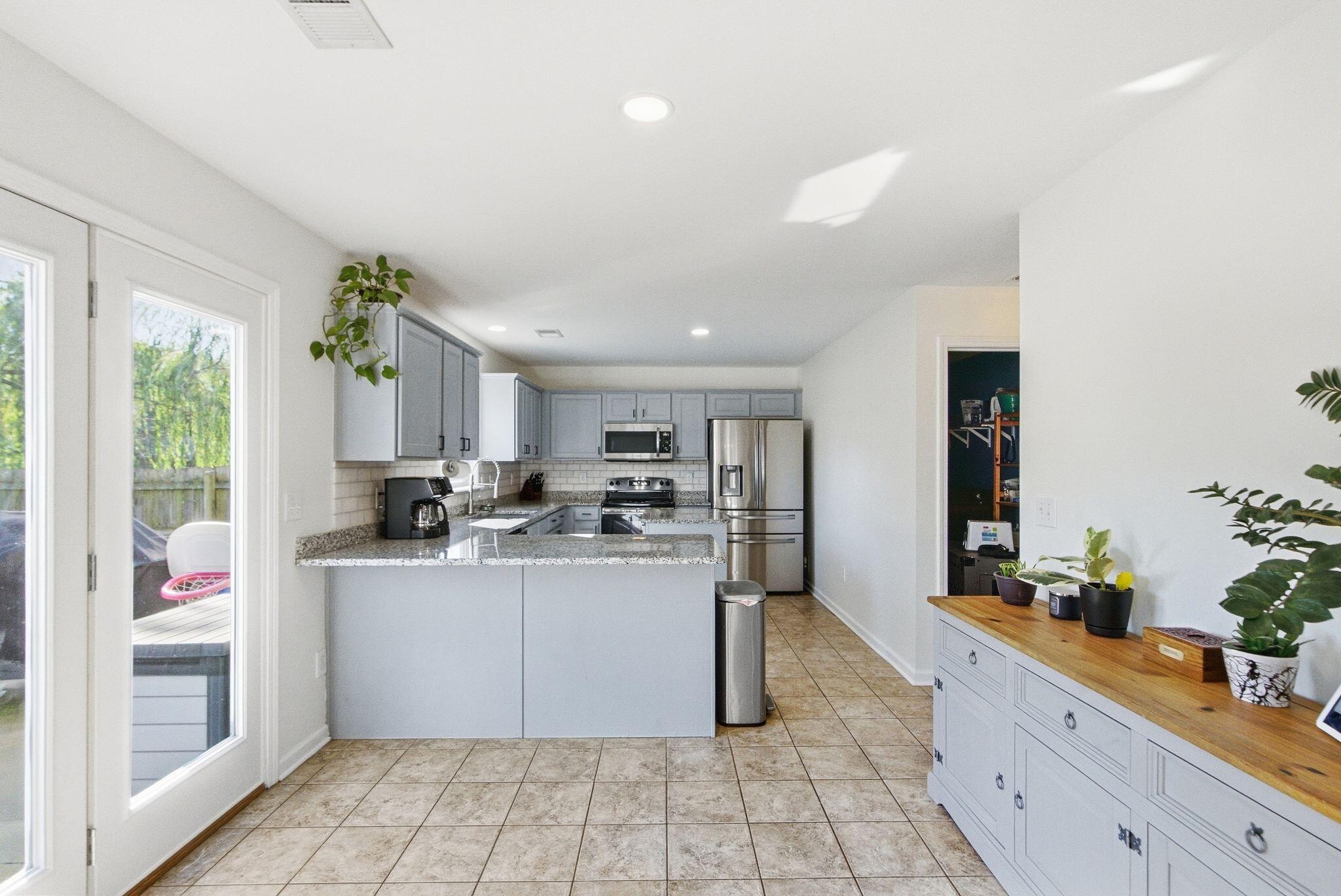 Kitchen with gray cabinets, granite peninsula, stainless steel appliances, and French doors to a deck.