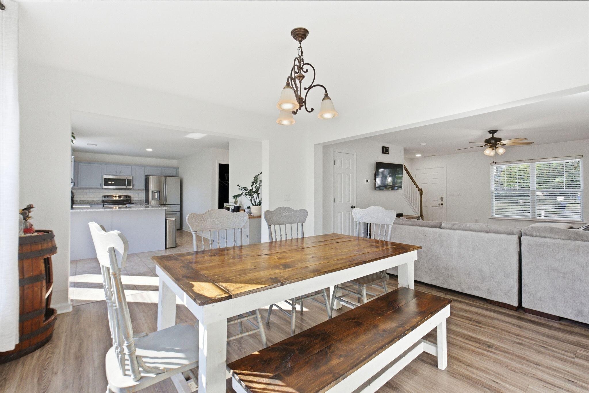 Open-plan dining room with a rustic wood table and bench beside the kitchen and living area.