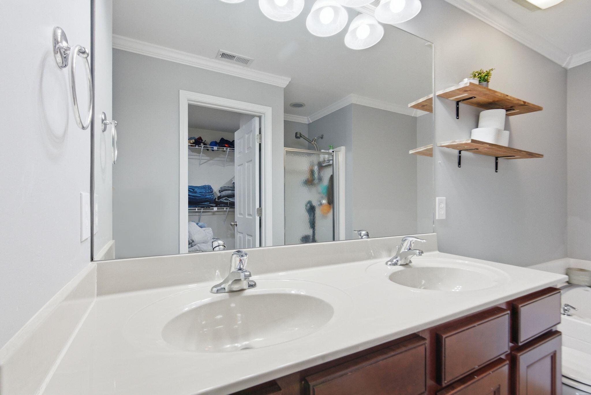 Bathroom with double sinks, dark wood cabinetry, and open wooden wall shelves.