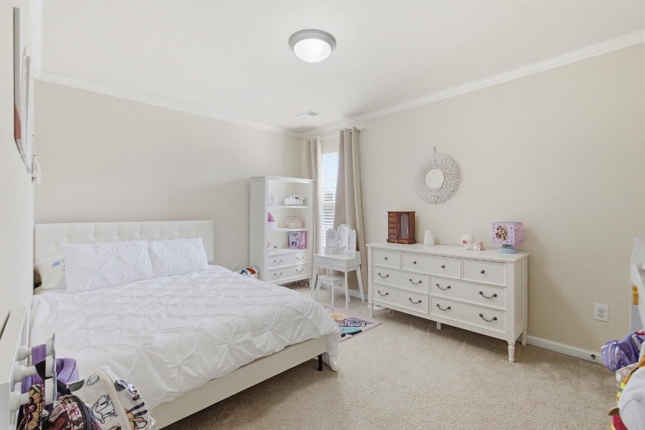 Bedroom with a white bed, dresser, and shelving beside a window.