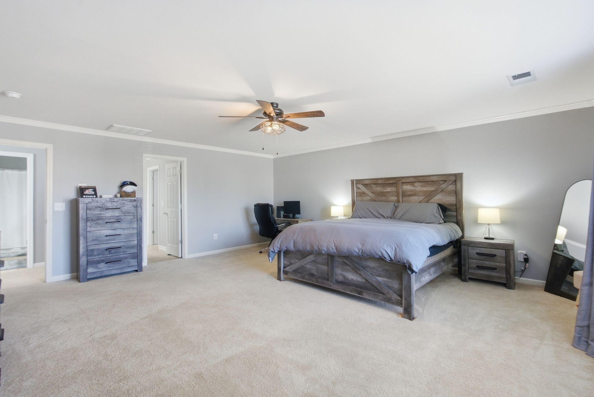 Furnished bedroom with a rustic wood bed, gray bedding, ceiling fan, and matching dresser.