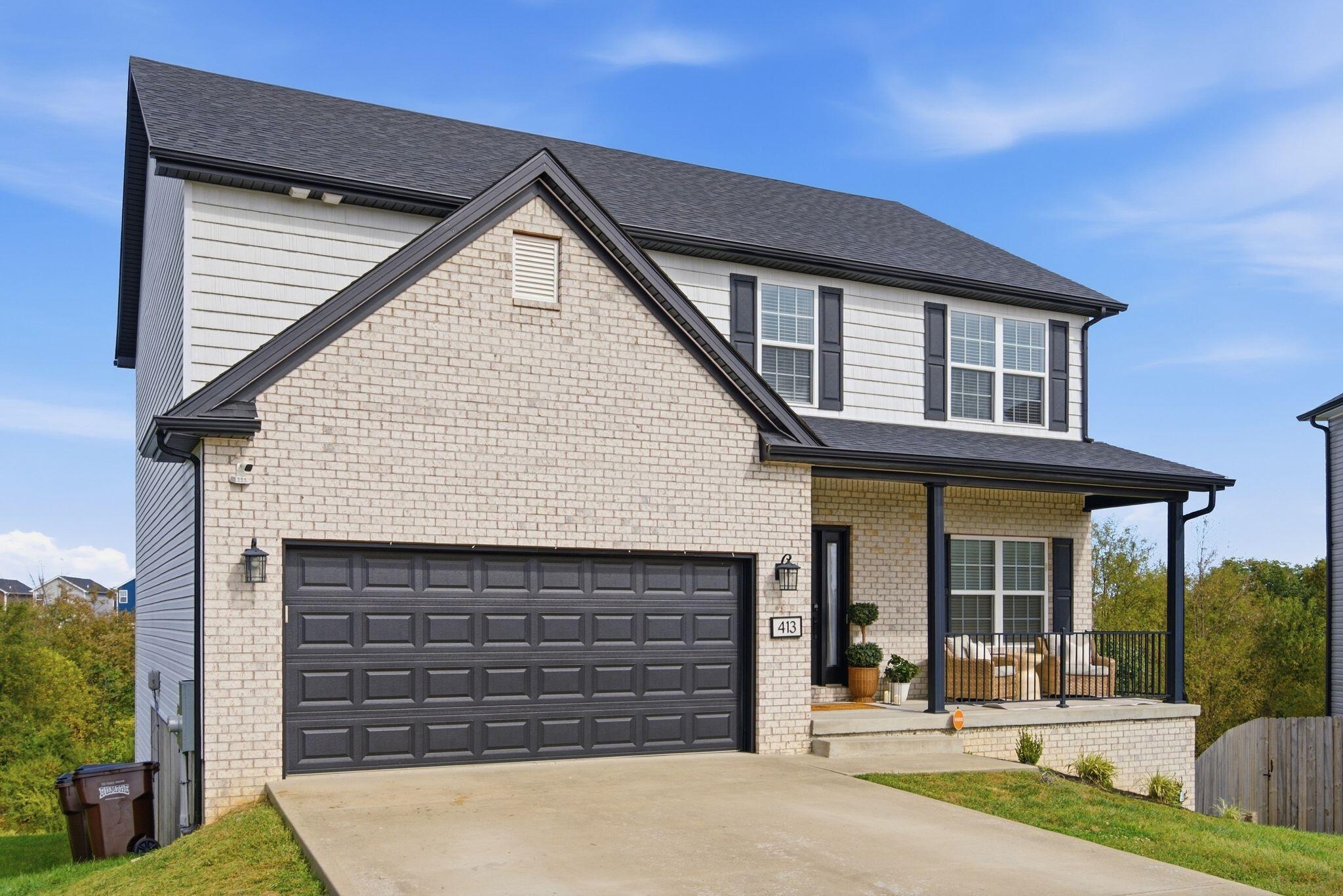 Two-story brick-front home with a wide double garage and covered porch.