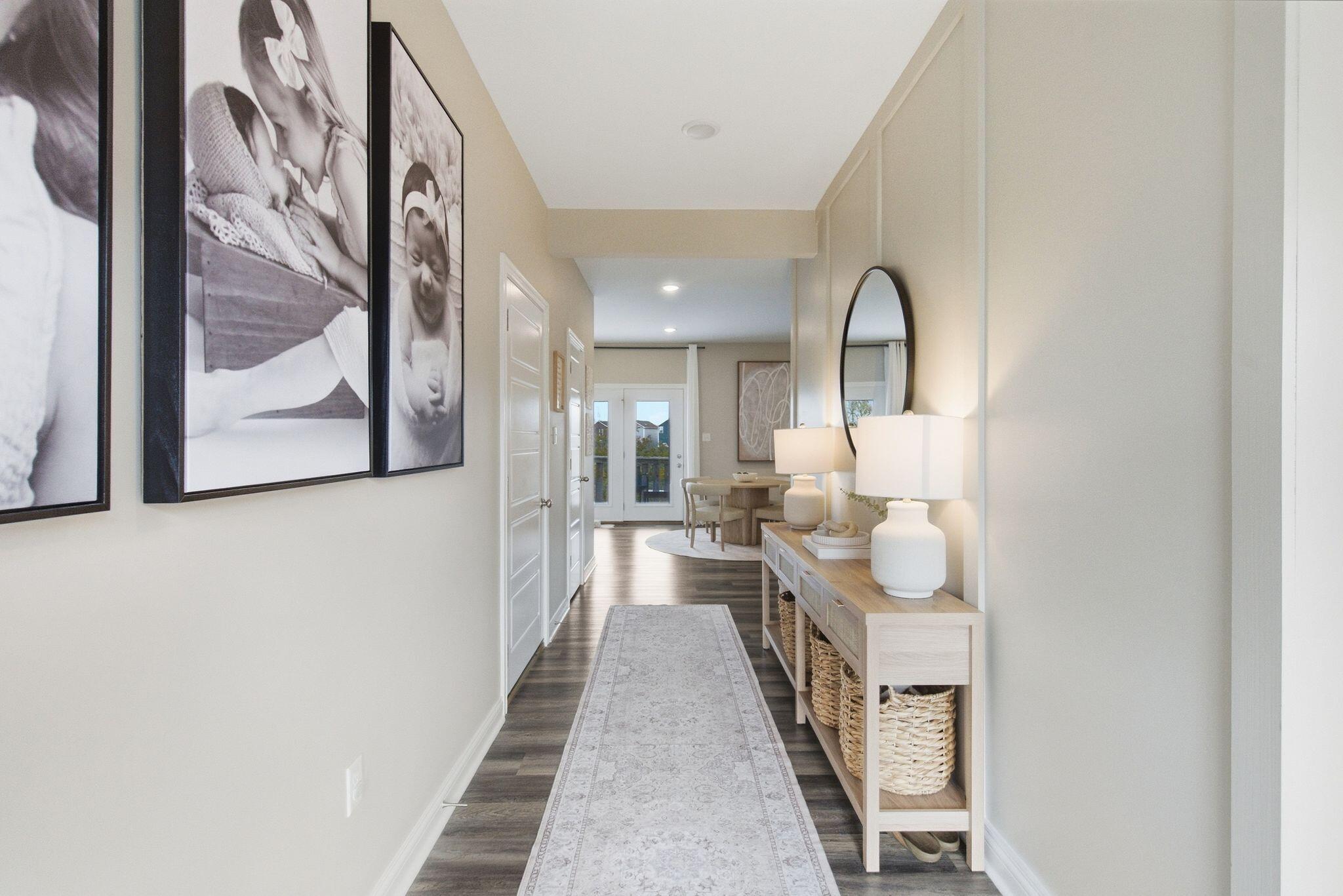 Entry hallway with a console table, framed family photos, and a view into the dining area.