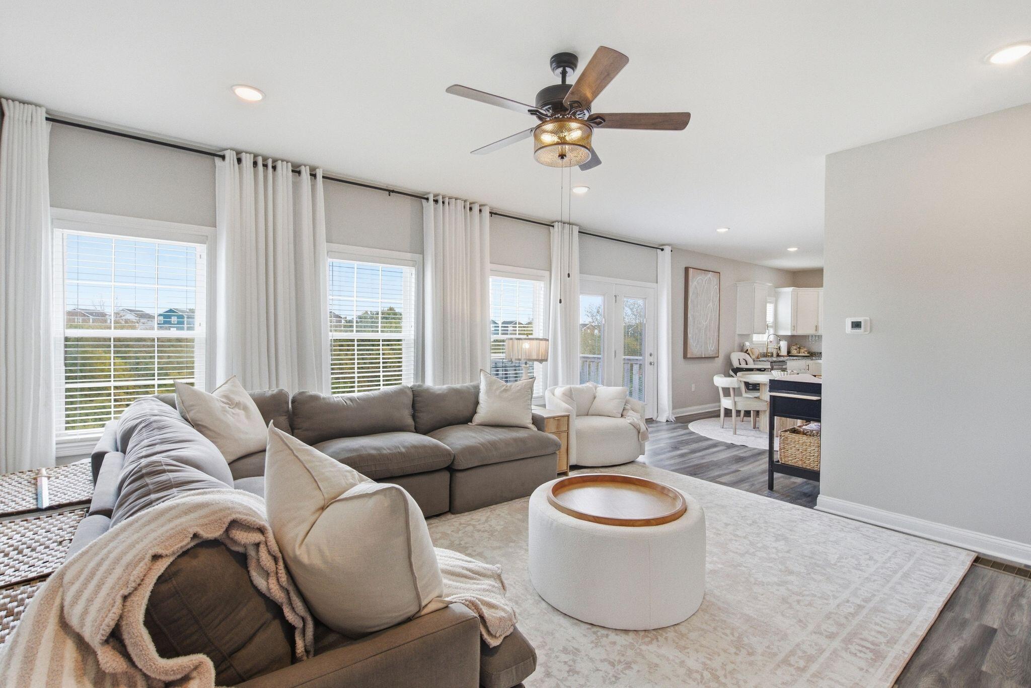 Living room with a large gray sectional, bright windows, and an open connection to the kitchen.